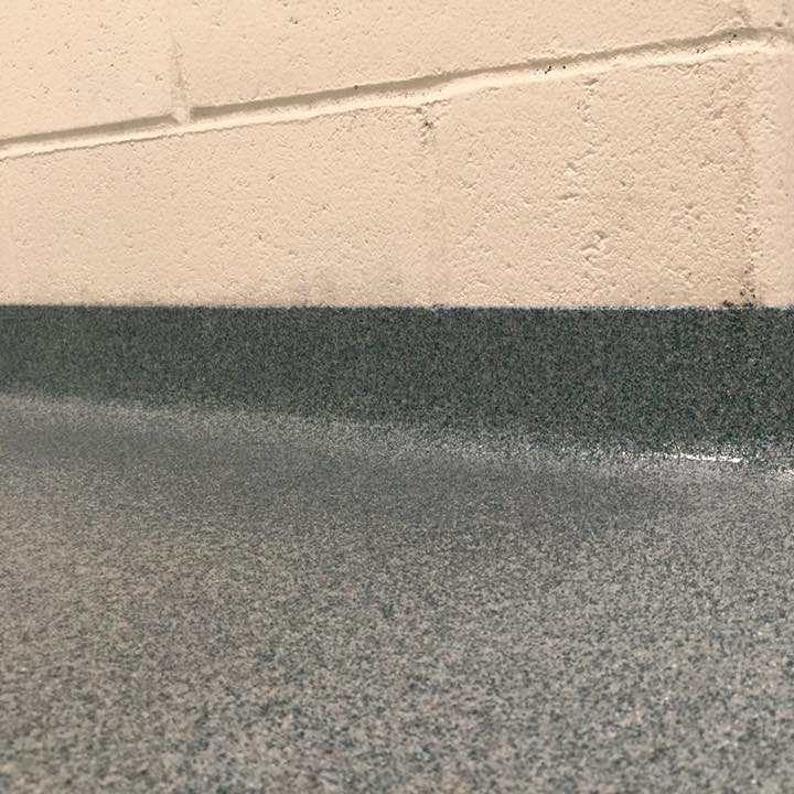 Seamless resinous flooring cove base at a floor-to-wall transition